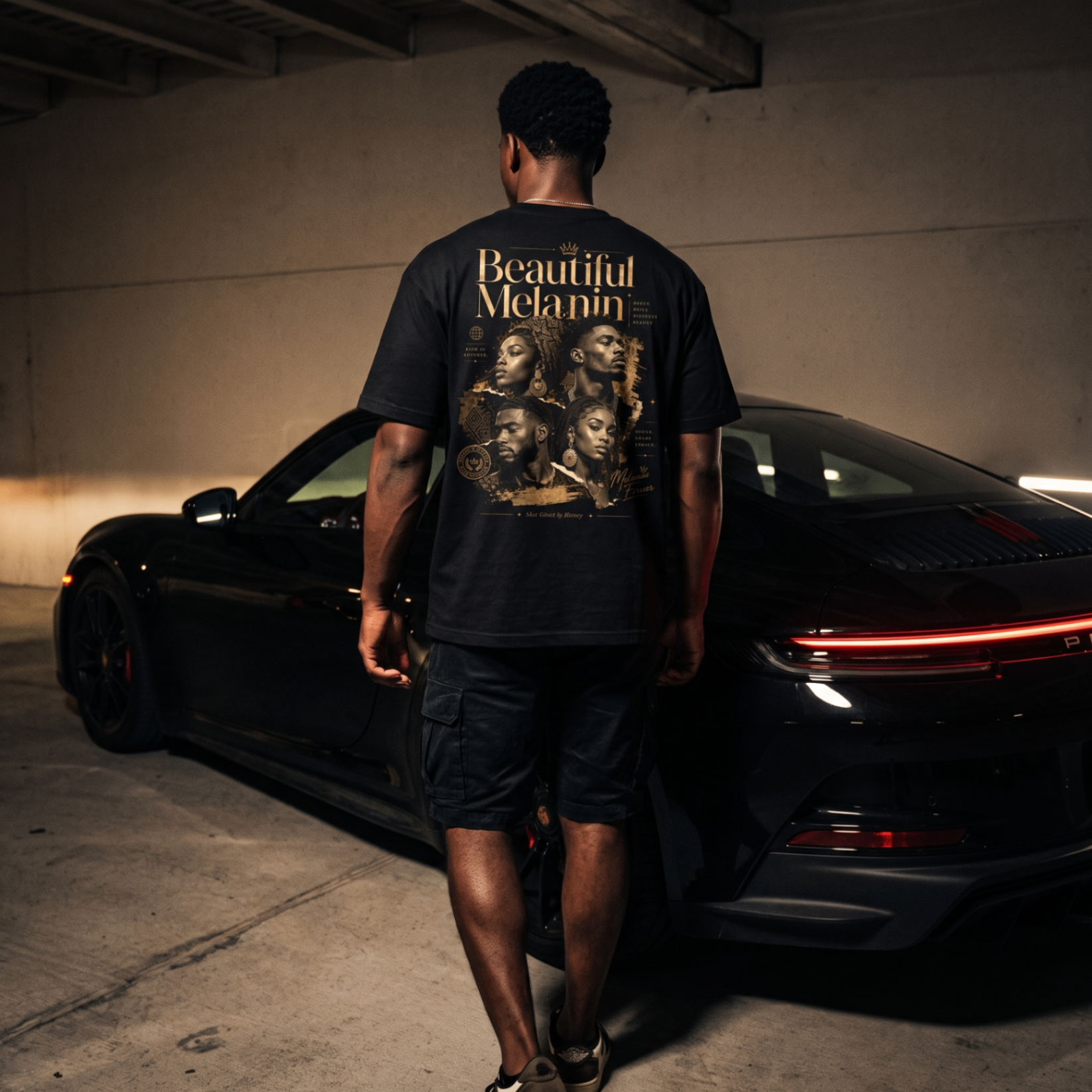Man wearing the Beautiful Melanin tee in front of a black Porsche at night.